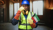 © Krakenimages.com - Man construction worker holding kuwaiti flag and raising gloved hand in building interior; pride unity celebration.
