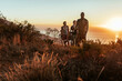 © Marko Geber - Group of friends hiking coastal trail at sunset