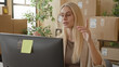 © Krakenimages.com - Woman wearing glasses at desktop computer, hand on shoulder while gesturing toward screen, cardboard parcels stacked in building; mild frustration.