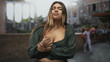 © Krakenimages.com - Woman clutching her wrist with hand at chest, visible cleavage against an ancient building with blurred tourists in plaza; unease.