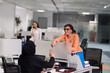 © .shock - Business colleagues collaborating and smiling in a modern open-plan office with woman in hijab