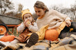 © ADDICTIVE STOCK - Sisters sitting with pumpkins on blanket in autumn