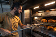 © ADDICTIVE STOCK - Artisan baker taking sourdough loaves from oven