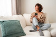 © ADDICTIVE STOCK - Woman relaxing on sofa using smartphone in bright living room