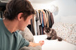 © ADDICTIVE STOCK - Young man reaching toward fluffy cat on bed at home