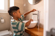 © ADDICTIVE STOCK - Hispanic boy washing hands at bathroom sink at home