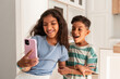 © ADDICTIVE STOCK - Hispanic siblings taking selfie on smartphone at home