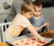 © JackF - Exciting activity for kids is working with dough. Boy and girl participate in preparation of pizza, help mother in kitchen..