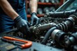 © miss irine - Car mechanic works on engine in auto repair shop. Technician fixes vehicle motor with tools. Man wears black gloves doing car maintenance and mechanical job.