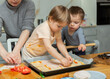 © JackF - Family are cooking italian pizza together in cozy home kitchen. Cute kids with happy mother are preparing food or meal for dinner