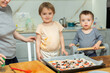 © JackF - Exciting activity for kids is working with dough. Boy and girl participate in preparation of pizza, help mother in kitchen..