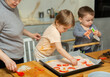 © JackF - Mother and her two sons roll out pizza dough together during fun family cooking activity