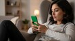 © Cenil - Woman using smartphone indoors with focused expression and comfortable seating