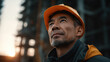 © Keopaserth - Asian man in orange hard hat looking up with thoughtful expression at construction site