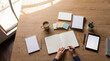 © Christine - Overhead shot of female hands writing notes in an open blank notebook on a wooden office desk with supplies.