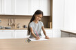 © fizkes - Beautiful girl painting pictures with colorful pencils in sketchbook, sit at kitchen table alone in cozy room, smile, enjoying drawing in album, looks focused and satisfied, spend free time on hobby