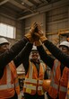 © Breezze - Group of diverse industrial workers joining gloved hands in celebration at a warehouse worksite for team achievement, workforce culture and safety training visuals