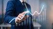 © DANG QUANG - Businessman pointing at a virtual holographic financial graph, symbolizing market growth and data insights.