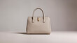 © Creative  - Elegant beige leather luxury handbag.​Sophisticated tote with gold hardware.​Minimalist designer purse studio shot.​Classic structured cream fashion accessory.​High-end leather bag on white.