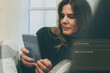 © Fabio Principe - A relaxed young woman sits comfortably at home using her smartphone to interact with an artificial intelligence chatbot, asking the AI to suggest a new novel with a surprising plot twist.
