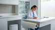 © AnastasiiaRozhmanova - Solo veterinarian completing handwritten progress notes in empty exam room after appointment, stethoscope on counter, used exam paper being 3