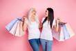 © deagreez - Happy women shopping together with colorful paper bags on pink background, friends enjoying retail therapy and laughter during a fun day out