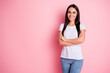 © deagreez - Confident smiling woman in white t-shirt and jeans standing with arms crossed against pink background, casual portrait conveying happiness and modern lifestyle
