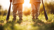 © Inai - Low angle view of two children holding baseball bats standing in grass at golden sunset on a sports field. Youth sport lifestyle banner about family values, teamwork and active childhood.
