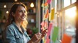 © Leonardo - Una mujer joven genera ideas para un proyecto con notas adhesivas de varios colores