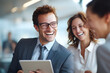 © hilmiyah - Business colleagues sharing a laugh over a tablet. Male executive and young female employee.
