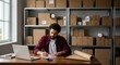 © Realis - Focused Man Working at Desk with Laptop and Boxes in Background, Preparing Packages for Shipping