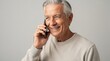 © PengAI - An elderly man with gray hair smiling while talking on a smartphone against a plain background.