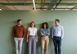 © Shahanara - Group of diverse young colleagues laughing and talking against a green wall
