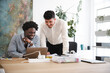 © Studio Marmellata - Two men collaborate on a project at a desk, one using a laptop while the other leans in to discuss.