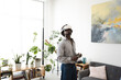 © Studio Marmellata - A young man wearing a virtual reality headset and holding controllers immerses himself in a digital world while standing in a modern living room.