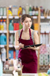 © JackF - Saleswoman in an apron checks the availability of goods in the supermarket warehouse using a tablet, she counts the leftovers of household goods and enters them into a spreadsheet