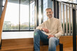 © Westend61 - Smiling man in casual clothing sitting on stairs in a modern office