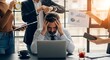 © alvi - Stressed businessman overwhelmed by colleagues in a busy office environment with laptop and paperwork