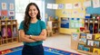 © Eve - Confident young female preschool teacher in bright classroom with educational posters and toys