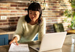 © Davor - Woman reviewing paperwork on laptop in home kitchen