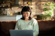 © Davor - Woman using laptop on sofa at home