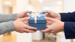 © Aurora Aesthetics - hands giving gift box white ribbon men business present corporate exchange formal occasion close up of two male human hands exchanging wrapped blue package with bow inside bright clean modern interior