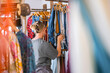 © shintartanya - Young woman choosing clothes in thrift-style boutique, conscious shopping, slow fashion, circular fashion, sustainable wardrobe and responsible consumption concept.