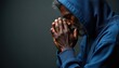 © miss irine - Elderly Black man with grey beard wears blue hoodie, clasps hands in prayer. He bows head in solemn devotion, seeking spiritual solace or guidance. Focused, contemplative mood.