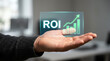 © eren - Hand displaying holographic return on investment concept with glowing ROI text and an ascending growth chart, symbolizing financial success and future business strategy