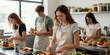 © Lubov - Young adults learn cooking in a modern kitchen class. Students prepare food together, practice chef skills. Diverse group enjoys culinary training teamwork in a casual setting.