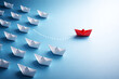 © aistudio - Red paper boat leading a fleet of white boats on a blue background symbolizing leadership business success teamwork innovation uniqueness and moving forward to victory