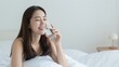 © CrazyJuke - Serene hydration moment: A young woman enjoys a moment of tranquility, sipping from a glass of water on a comfortable bed, epitomizing the essence of a healthy lifestyle.