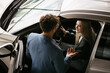 © dsheremeta - Car salesman assisting woman trying new automobile