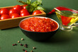 © Pixel-Shot - Bowl of tasty tomato sauce and ingredients on green background, closeup